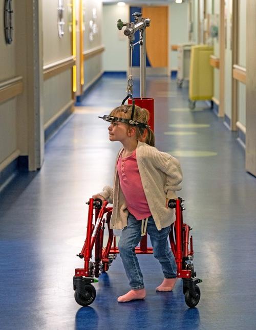 艾比·弗劳尔斯在美国儿童健康中心的大厅里穿行 & 在女性医院的光环重力牵引定制助行器的帮助下. 